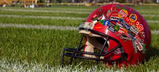 Image of football helmet covered in logos on grass field